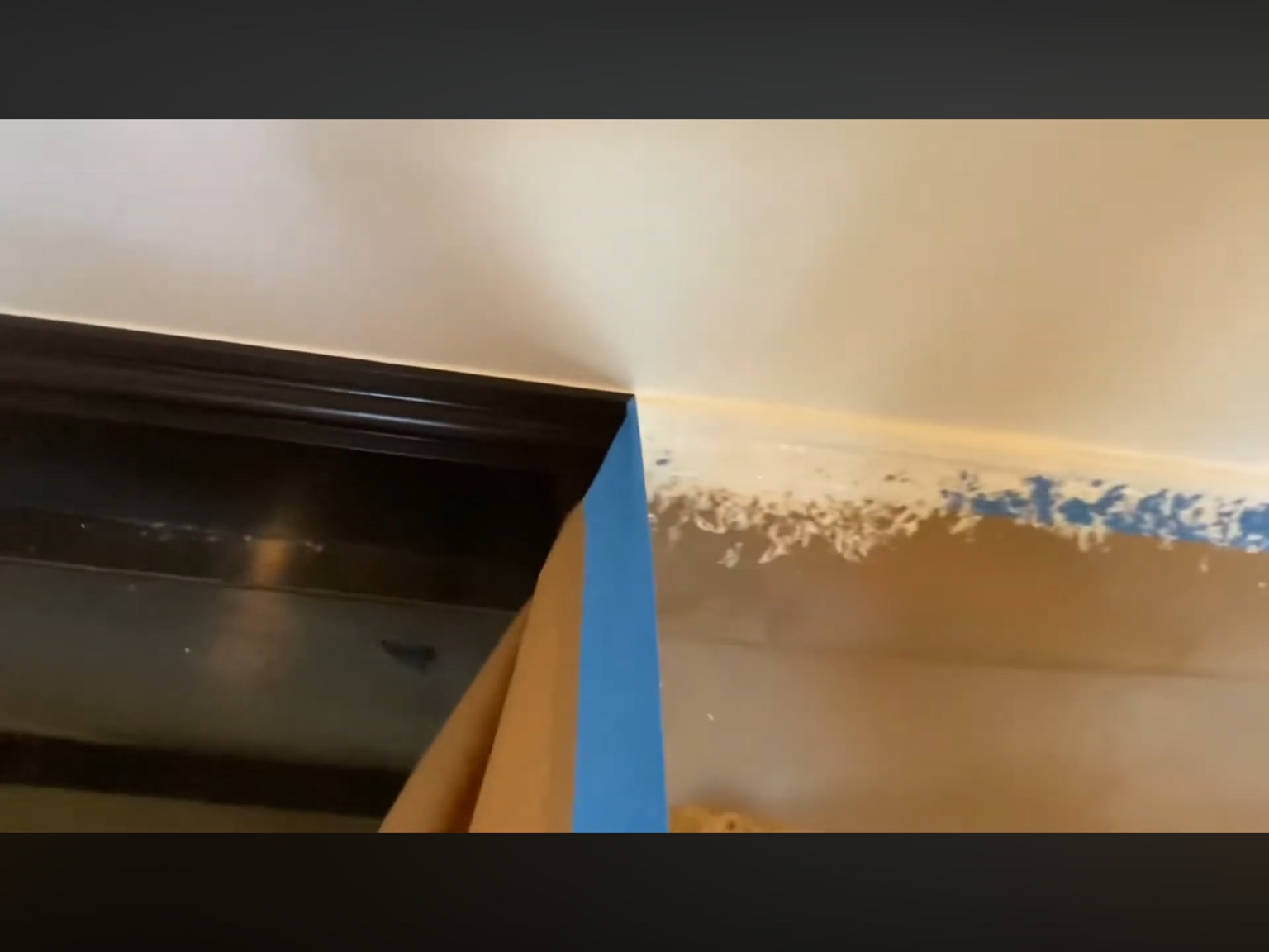 Close-up of tape removal revealing a crisp edge above black baseboards